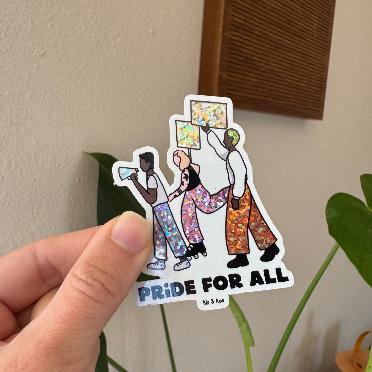 Sticker with colorful design and text held by a hand on a neutral background